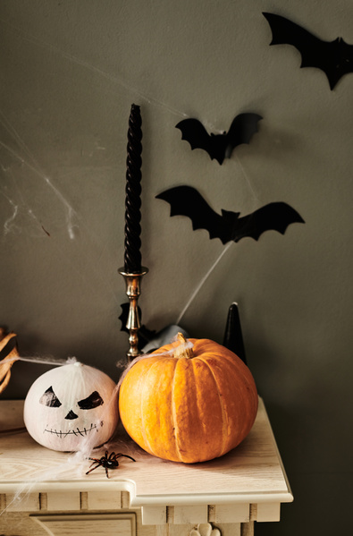 Halloween Pumpkins Stand next to Candles and Bats Are Attached Above Them